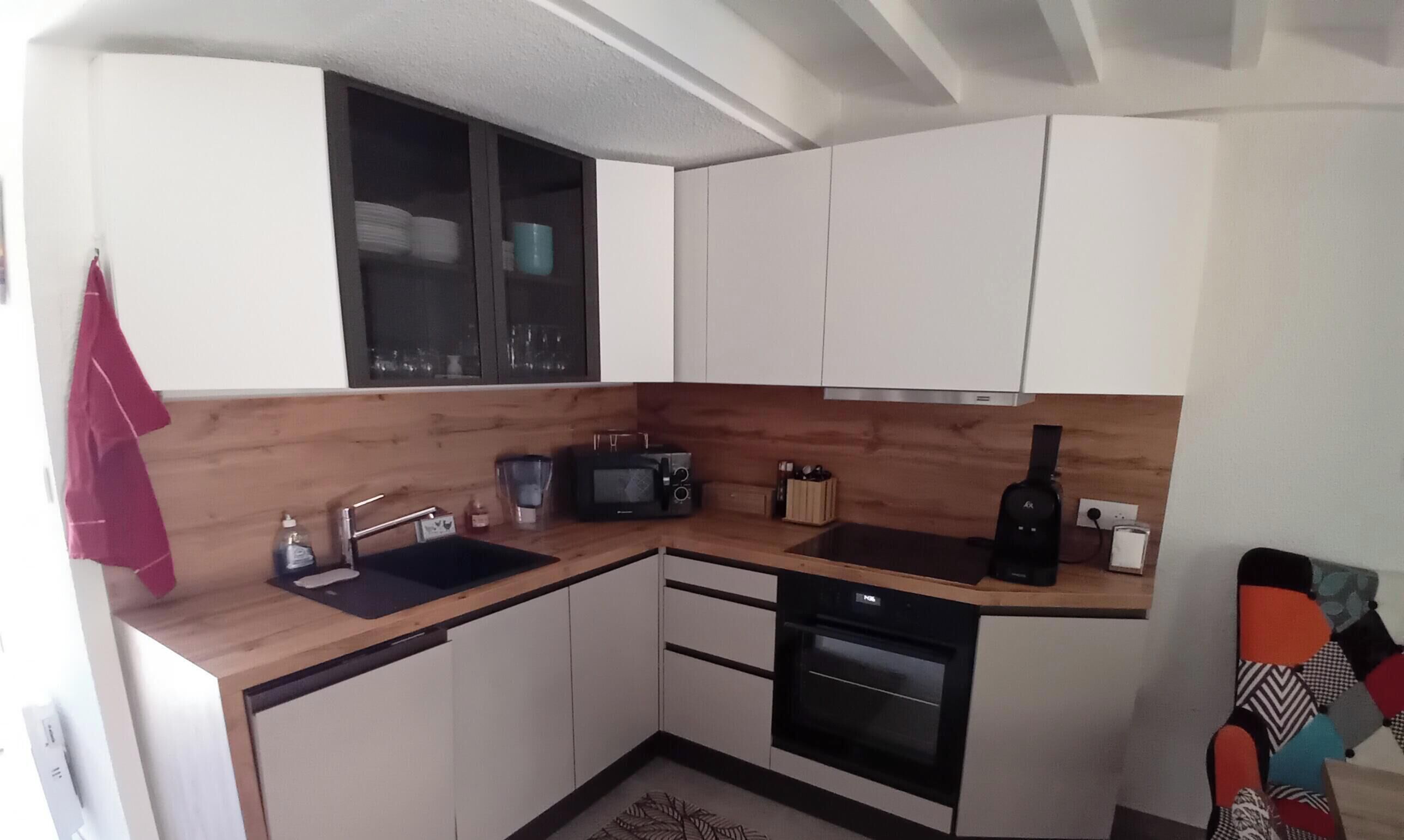 A compact kitchen with white cabinets, a microwave, a sink, and a stove.