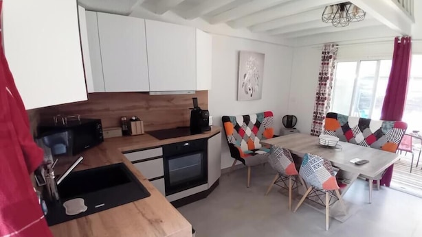 Una cocina moderna con armarios blancos, encimera de madera y un comedor con sillas coloridas y una mesa.