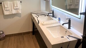 Une salle de bain avec un lavabo blanc, un grand miroir et un porte-serviettes.
