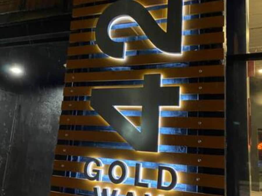 Een bord waarop 'GOLD WAY' in blauw licht staat.