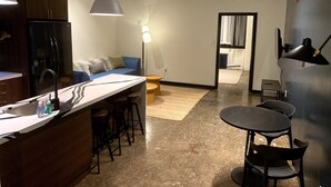 Une cuisine moderne avec un coin bar, un espace salon avec un canapé et une table à manger avec des chaises.