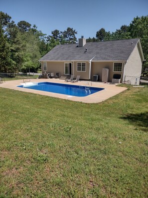 A house with a swimming pool, a covered patio, and a fenced yard.
