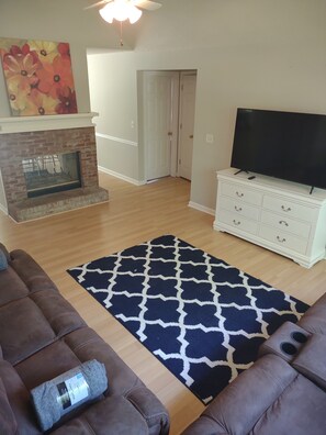 A living room with a fireplace, a television on a white cabinet, and two brown sofas.