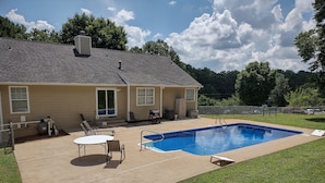 Una casa con piscina, un patio cubierto y un patio cercado.