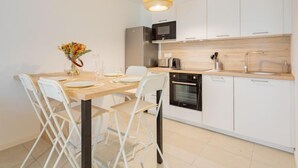 Una cocina moderna con armarios blancos, encimera de madera, horno empotrado y lámpara colgante.