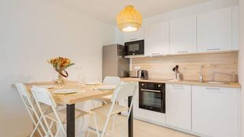 Een moderne keuken met witte kastjes, een houten aanrechtblad, een inbouwoven en een hanglamp.