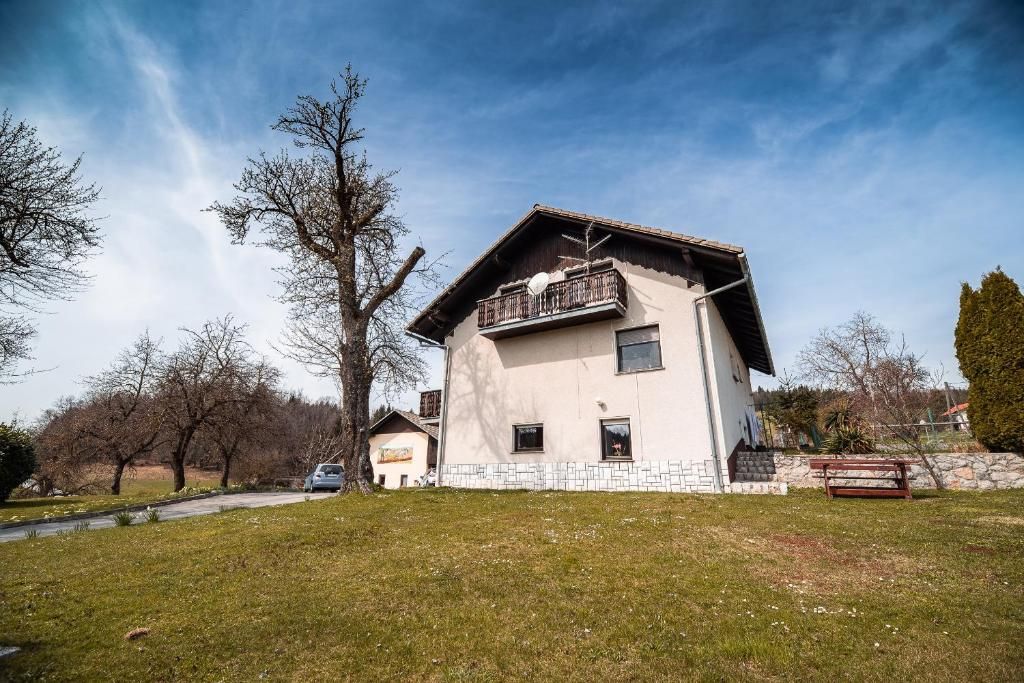 Ein zweistöckiges Haus mit Balkon, gepflasterter Auffahrt und Rasengarten.