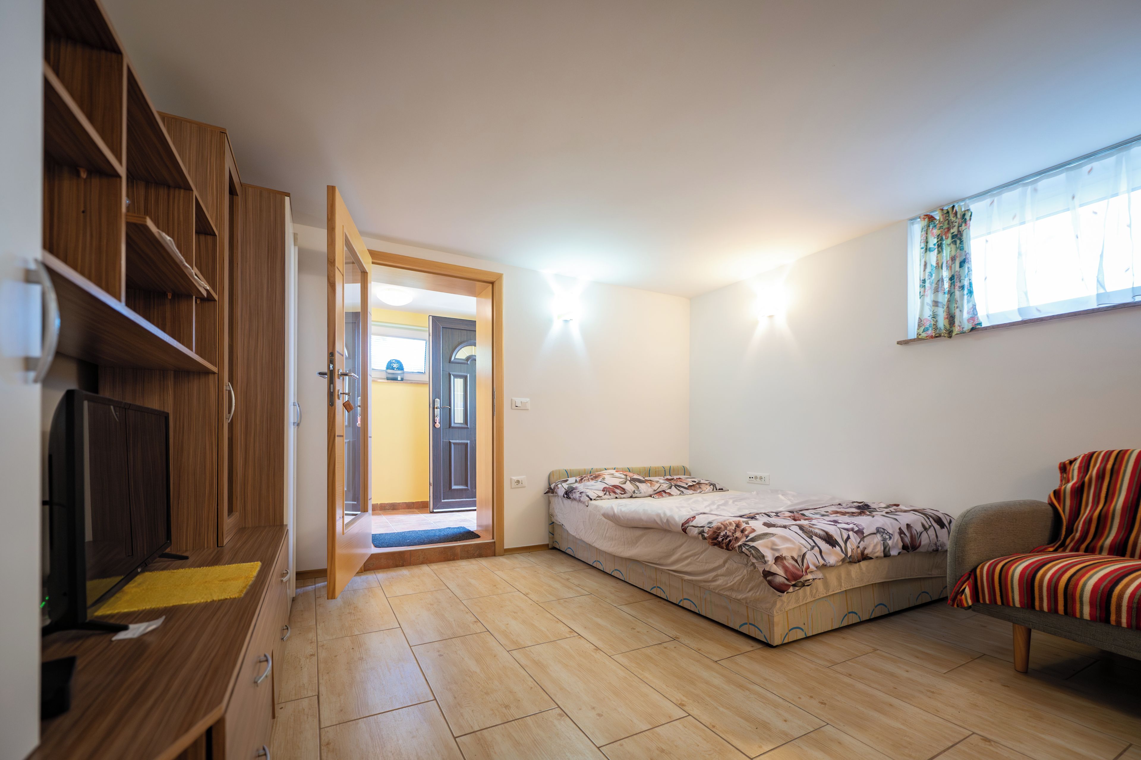 Une chambre de taille modeste, équipée d’un lit, d’une télévision et d’une armoire.