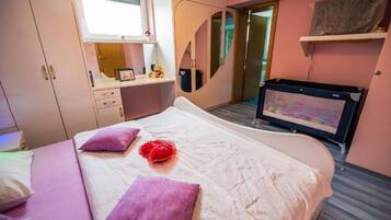 Habitació d'hotel amb llit, escriptori, armari i televisió.