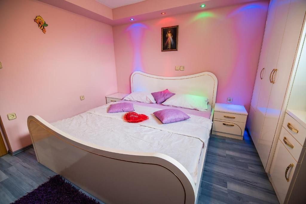 Un dormitorio con cama, mesitas de noche, armario y un cuadro colgado en la pared.