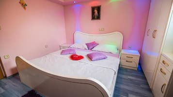 Un dormitorio con cama, mesitas de noche, armario y un cuadro colgado en la pared.