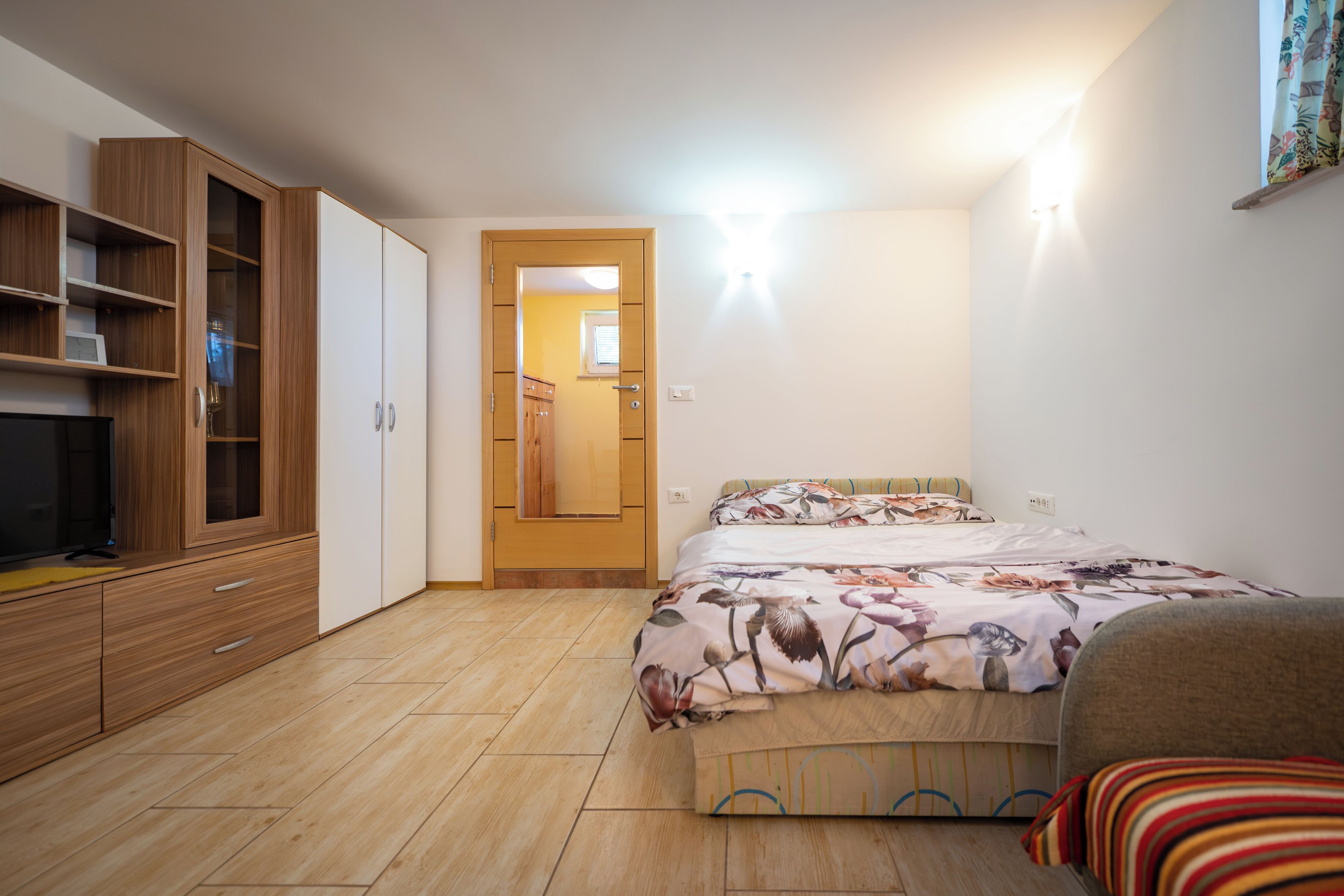 Un dormitorio con cama, armario de madera y televisión.