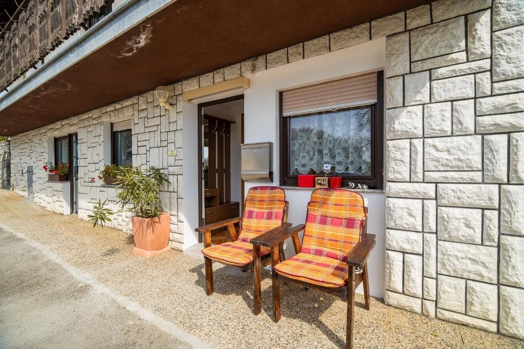 Un edificio con facciata in pietra, un ingresso e due sedie all'esterno.