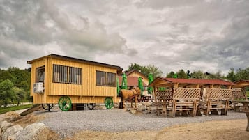 A wooden building with a cart and a horse, surrounded by outdoor seating areas.