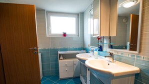 Un baño con dos lavamanos, una ventana y un espejo.