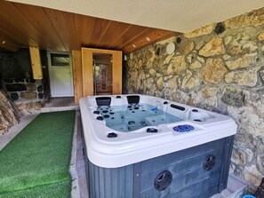 A hot tub with a control panel, surrounded by stone walls and wooden beams. - Farm Stay Ana (Ivancna Gorica)