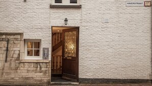 Un bâtiment en briques blanches, avec une porte en bois et une petite fenêtre.
