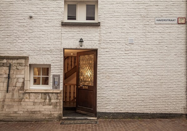 A white brick building with a wooden door and a small window. - Luxury Suites Riverside Residence (Antwerp)