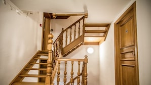 Un escalier en bois avec une rampe et une porte sur laquelle est apposée une enseigne.