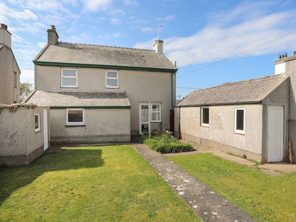 A two-story house with a paved driveway and a small garden area.