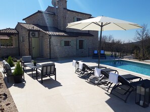 A stone villa with a swimming pool, outdoor seating, and a large umbrella. - Modern Stone Villa with Saline Pool in peaceful natural setting! (Bankovci, Groznjan)