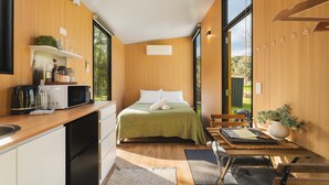 Een moderne slaapkamer met een bed, een klein bureau en een raam.
