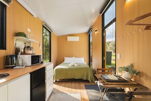 Ein modernes Schlafzimmer mit einem Bett, einem kleinen Schreibtisch und einem Fenster.