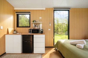 A compact kitchen with a dishwasher, microwave, and a small shelf with glassware. - The Wollombi Wanderer by Tiny Away (Wollombi)