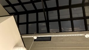 Een plafond met een raster van ramen en een wit paneel.