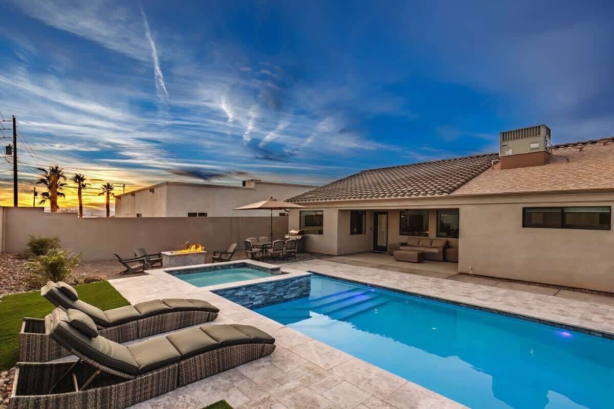 A modern house with a swimming pool, outdoor furniture, and a clear sky.