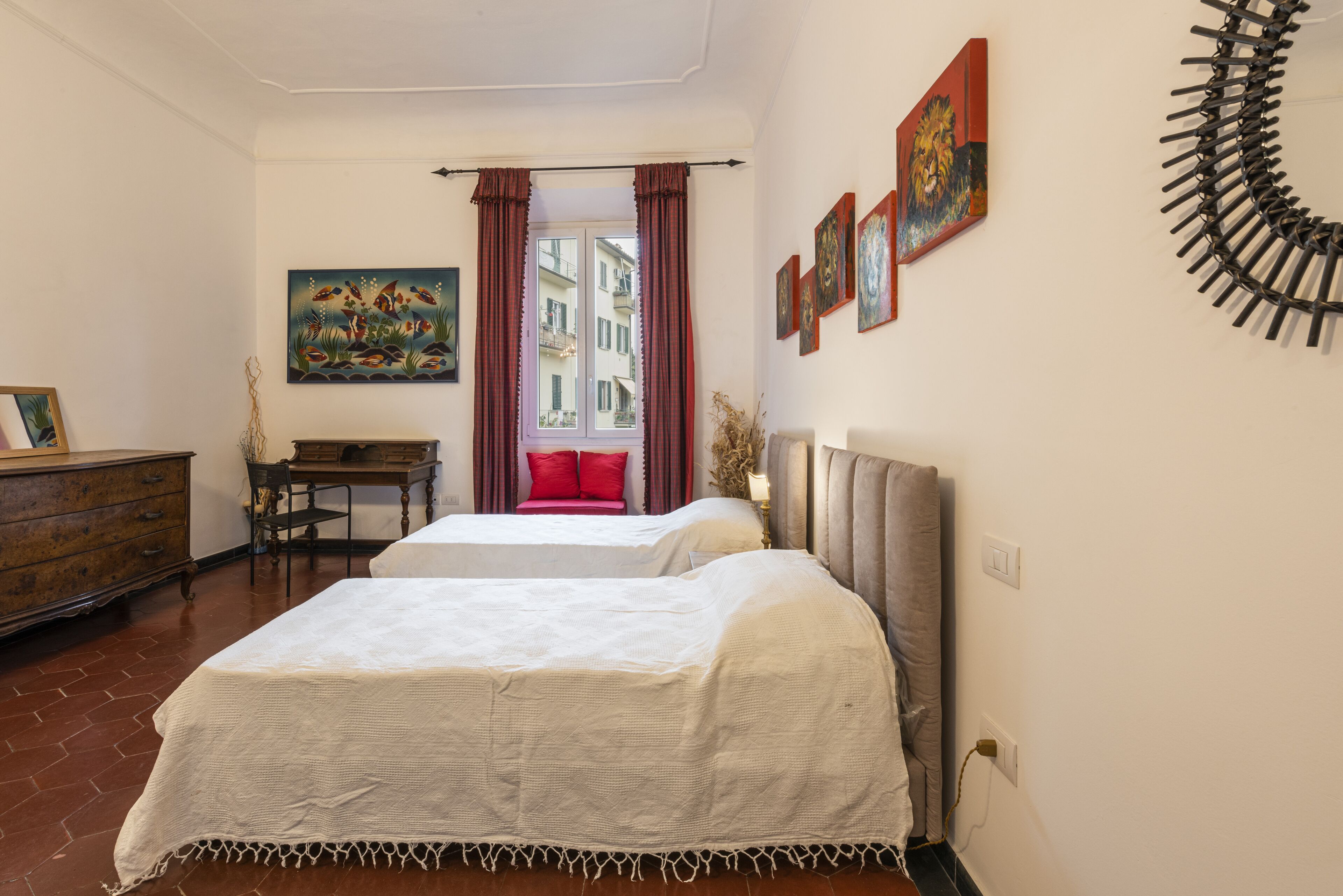 A hotel room with two beds, a desk, a chair, a dresser, and a window with curtains.
