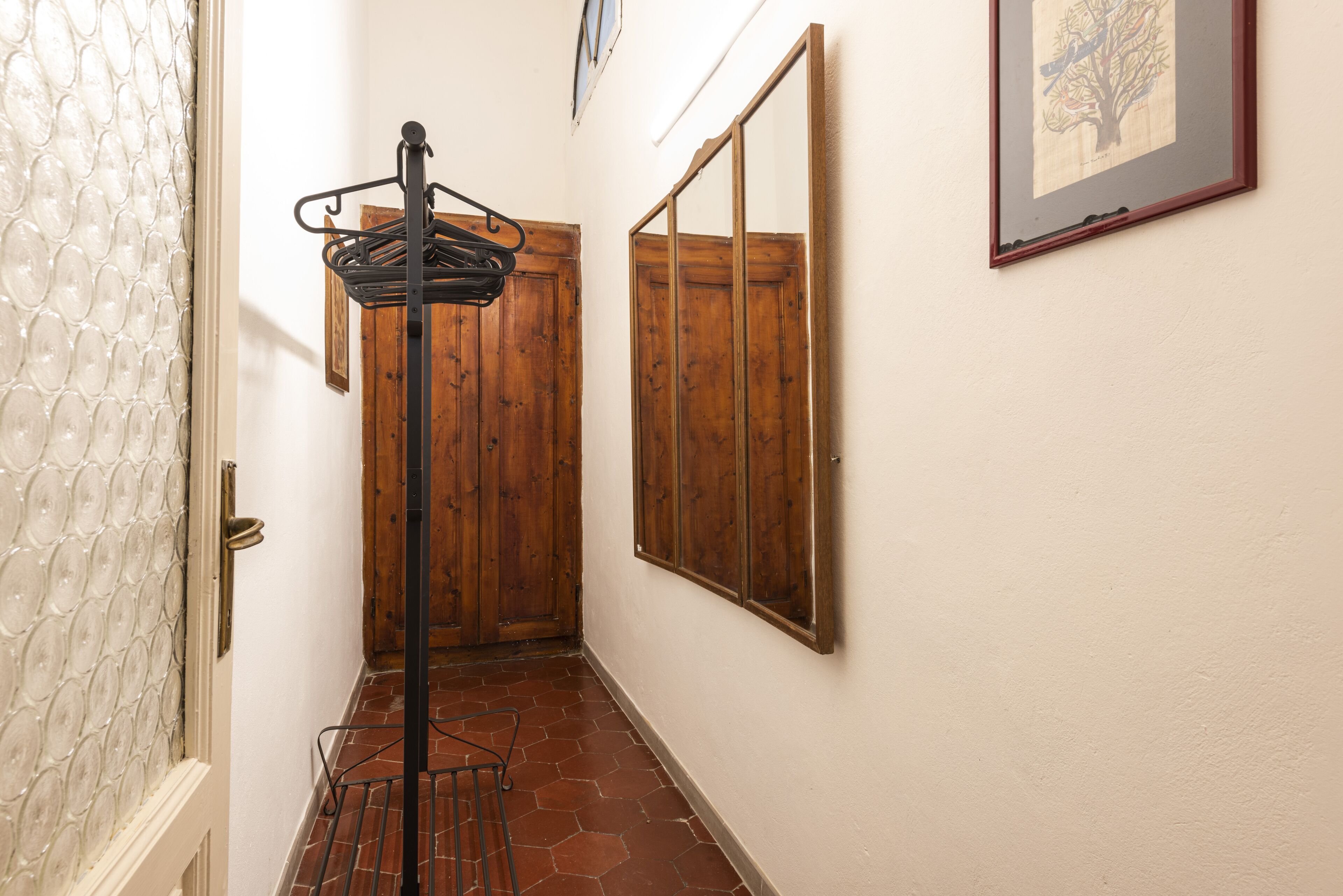 A hallway with a wooden door, a metal rack, and a framed picture on the wall.