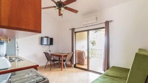 A compact living space with a kitchenette, a dining area, a green sofa, and a balcony with a view. - Tranquil Jungle Stay with Breathtaking views, Minutes to Dominical Beach (San Jose Province)