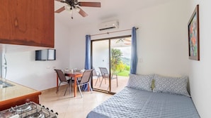 A room with a bed, a dining table with chairs, a kitchen area with a stove, a ceiling fan, and a view through a sliding glass door. - Tranquil Jungle Stay with Breathtaking views, Minutes to Dominical Beach (San Jose Province)