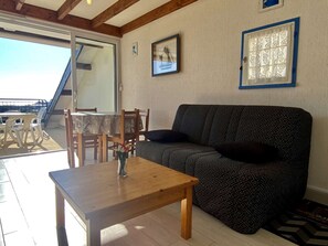 A living room with a wooden table, a patterned sofa, and a dining area with chairs and a table.