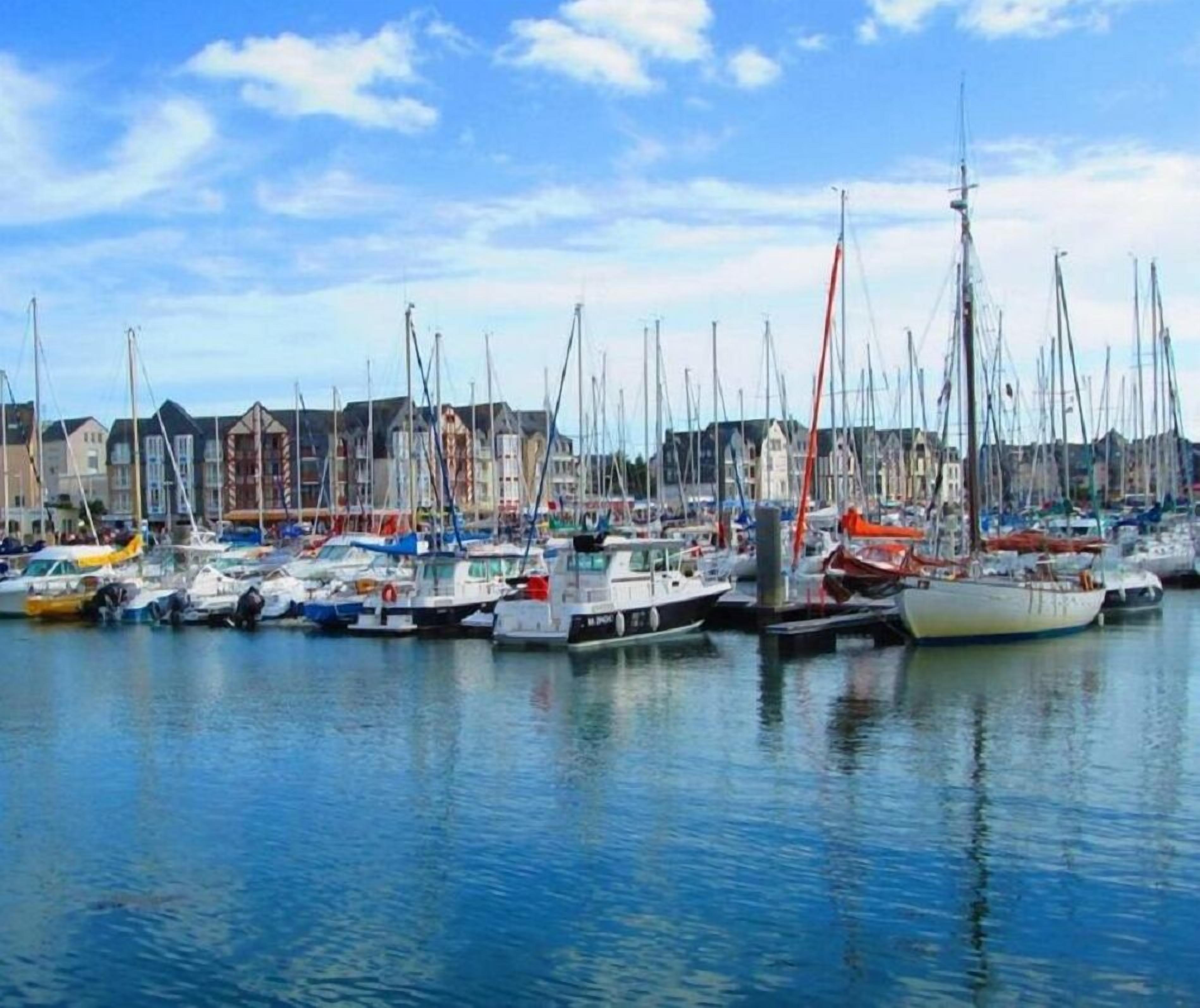 A marina with various boats docked, surrounded by buildings.
