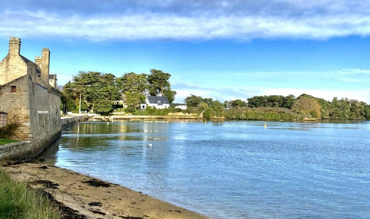 Vista al río con un edificio de piedra y una casa al otro lado del agua.