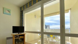 A room with a large sliding glass door leading to an outdoor patio with a white table and chairs. - T2 on Port du Crouesty with balcony for vacation rental (ARZON)