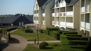 A multi-story hotel with a symmetrical facade, balconies, and a well-maintained garden area. - T2 on Port du Crouesty with balcony for vacation rental (ARZON)