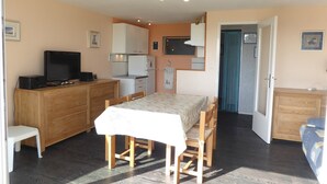 A compact room with a kitchenette, a dining area, and a television.