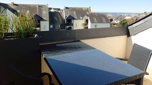 A rooftop terrace with a metal table and chairs, a potted plant, and a view of surrounding buildings. - Apartment for 4 sea view near Crouesty port (ARZON)