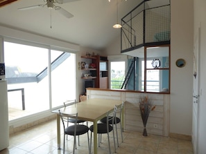 Un espace repas comprenant une table et des chaises, un ventilateur de plafond et une vue sur l’extérieur.