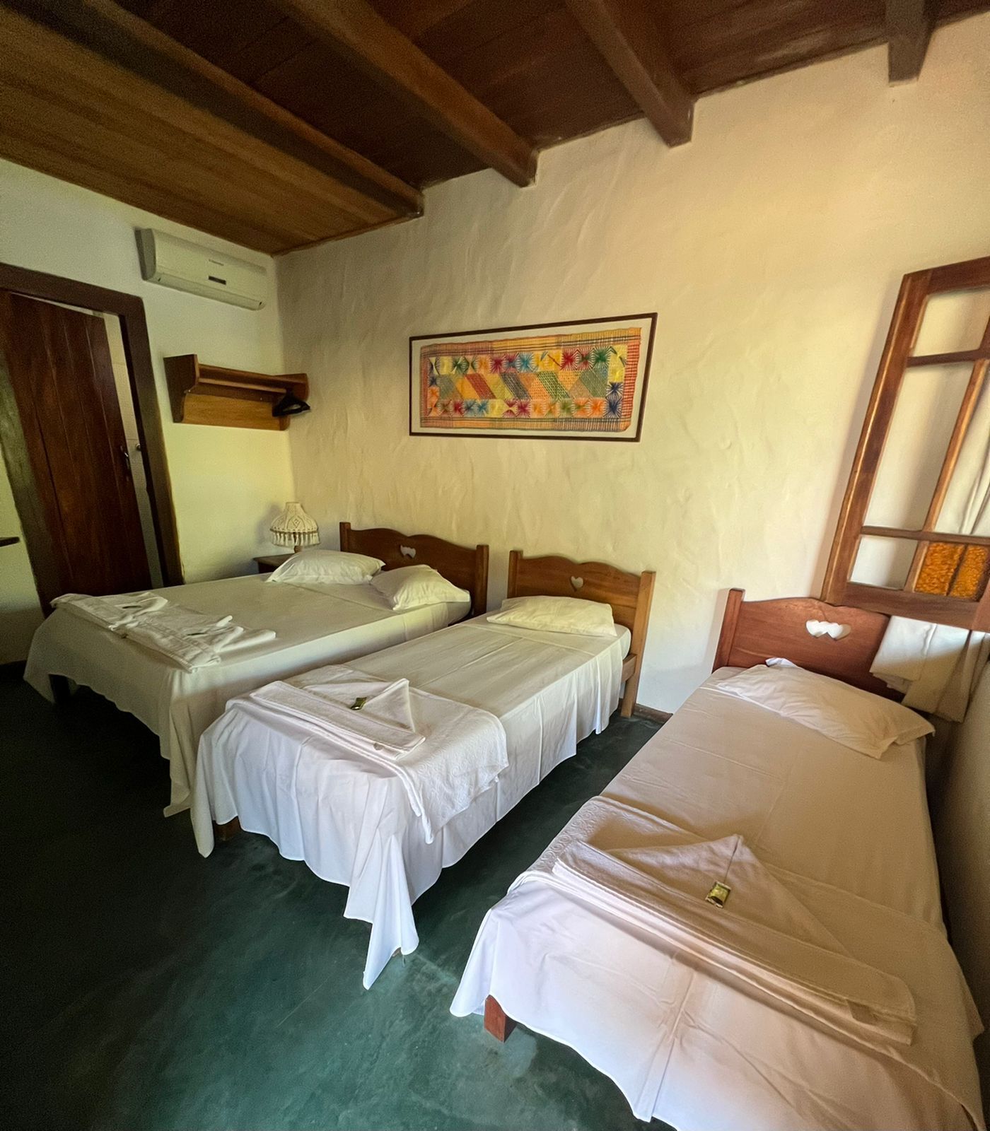 Een kamer met twee bedden, een houten plafond, een aan de muur hangend schilderij en een deur.