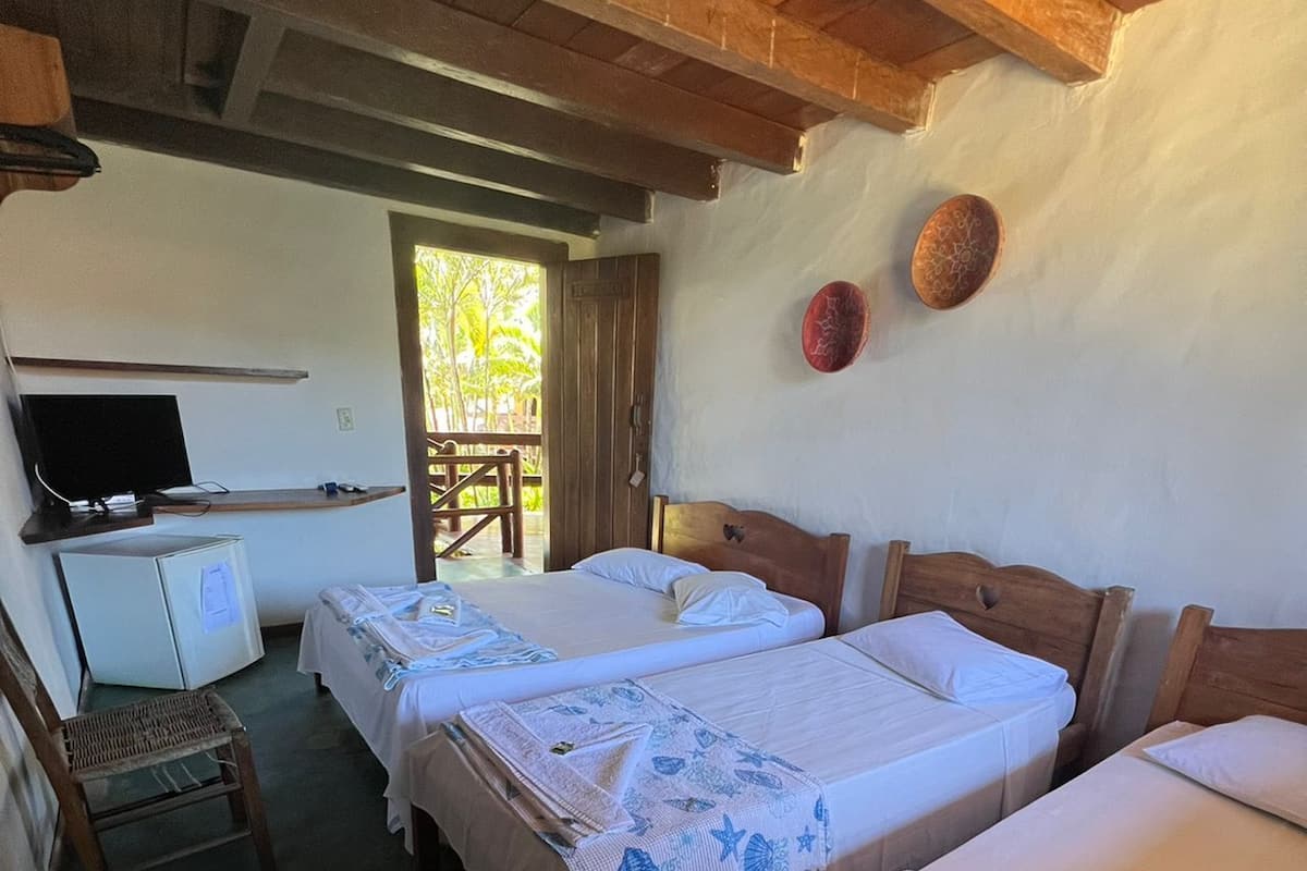 A room with three beds, a desk, a television, and a small refrigerator.
