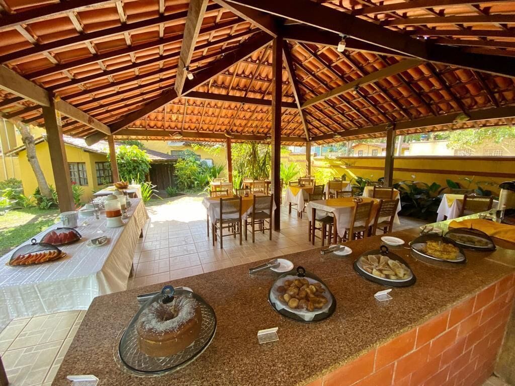 An outdoor dining area with a covered patio, tables set for meals, and a variety of dishes displayed on the counter.