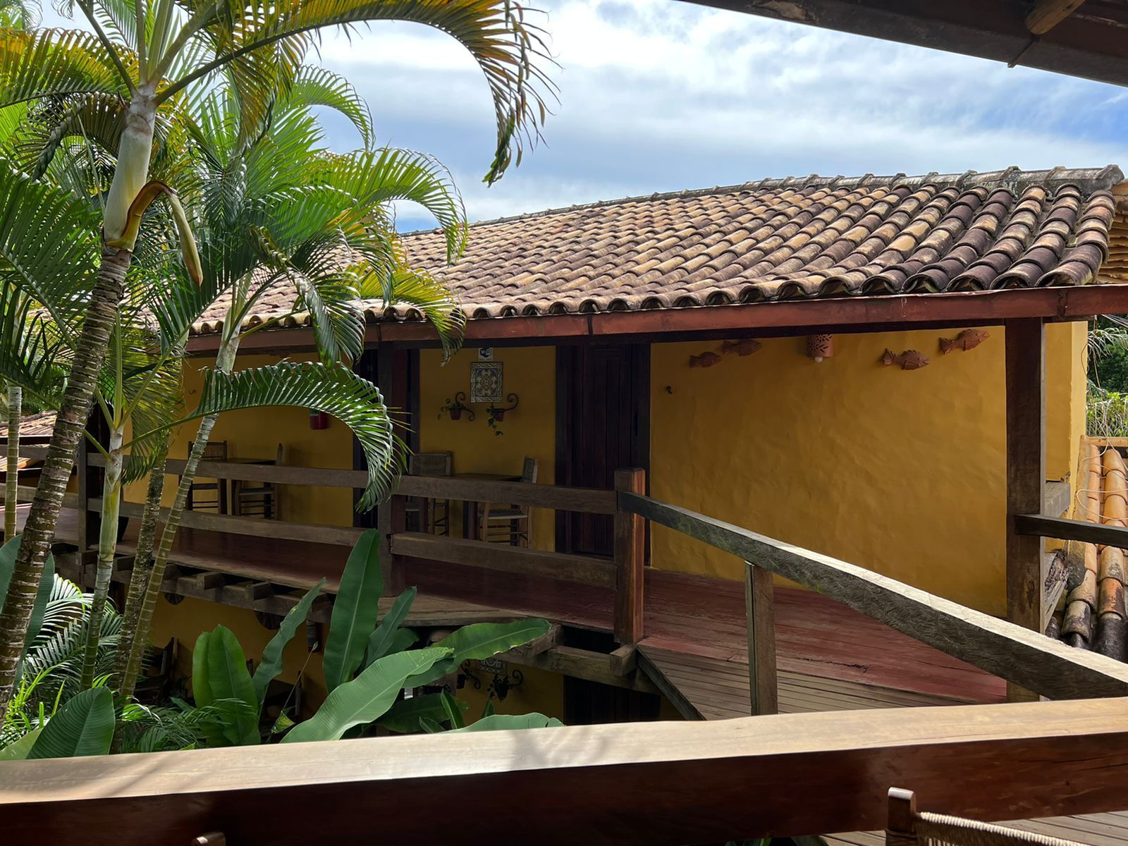 A yellow building with a tiled roof and a wooden deck.