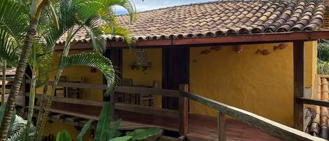 A yellow building with a tiled roof and a wooden deck.