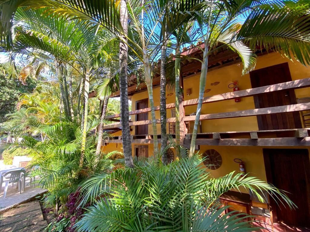 Un edificio amarillo con balcón de madera, rodeado de exuberante vegetación tropical.