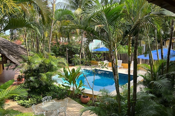 Una piscina al aire libre, sombrillas, sillones reclinables de piscina