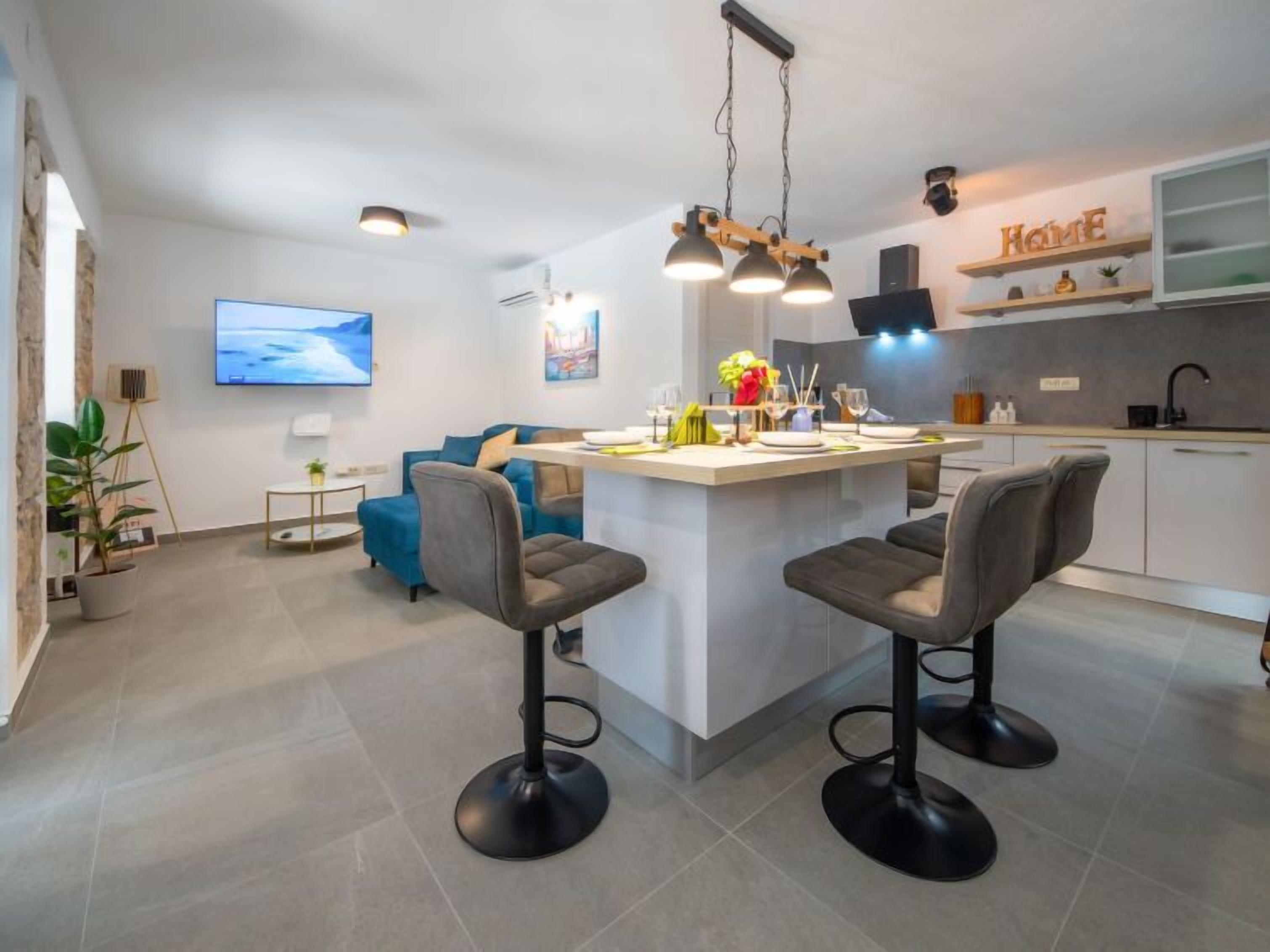 A modern kitchen with a central island, bar stools, and a dining area.